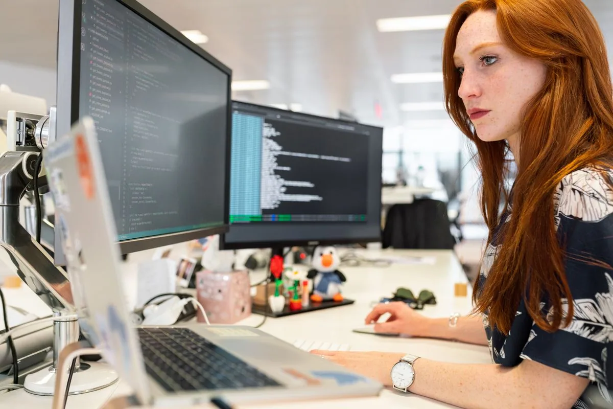 Developer monitoring a small business website on dual screens, keeping it updated, backed up, and online